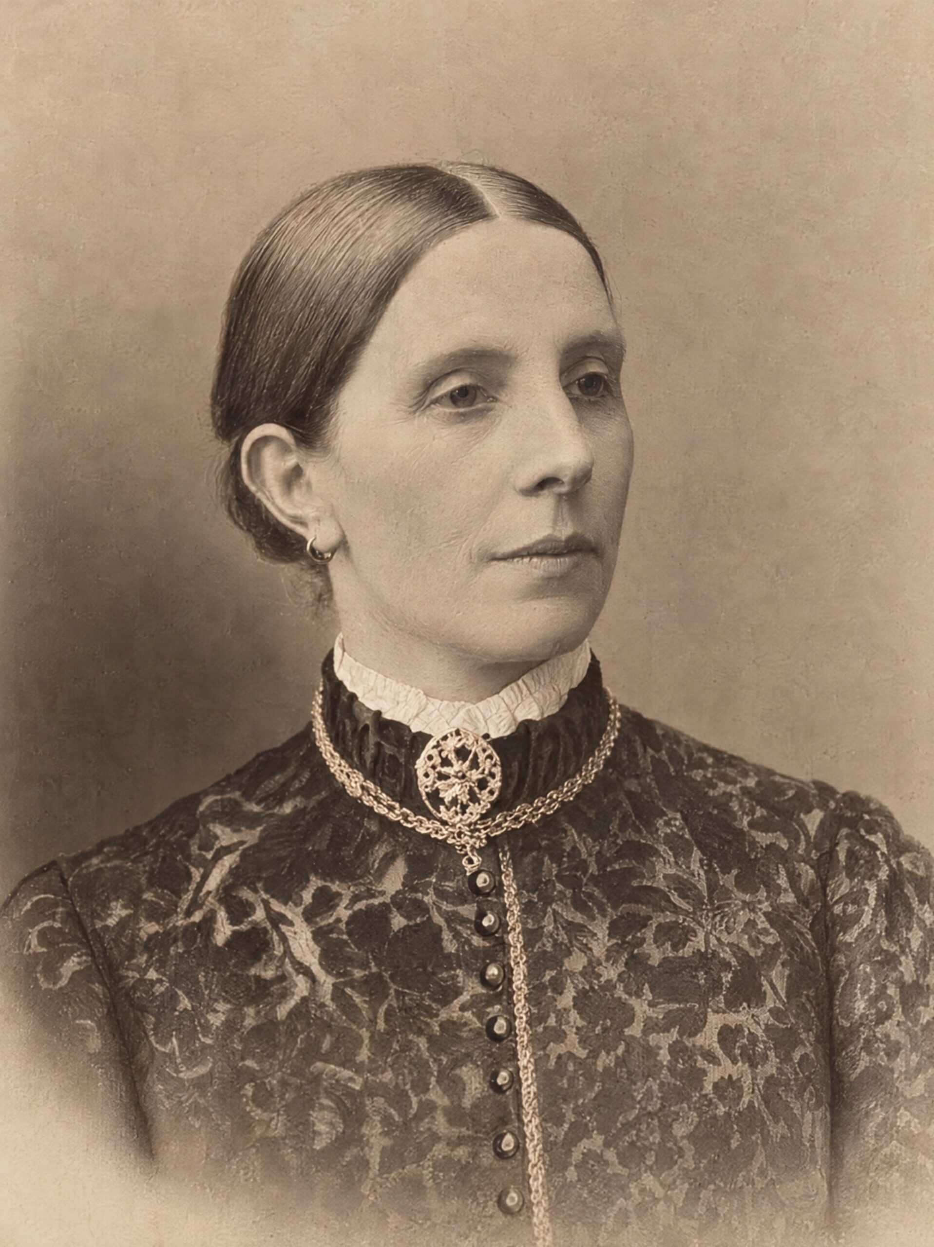 Restored sepia portrait of a woman, with her face, lace collar and jewellery visible.